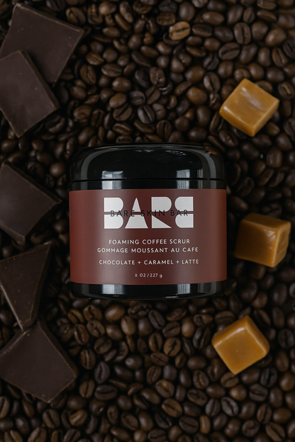 Jar of Bare Skin Foaming Coffee Scrub surrounded by coffee beans and chocolate pieces